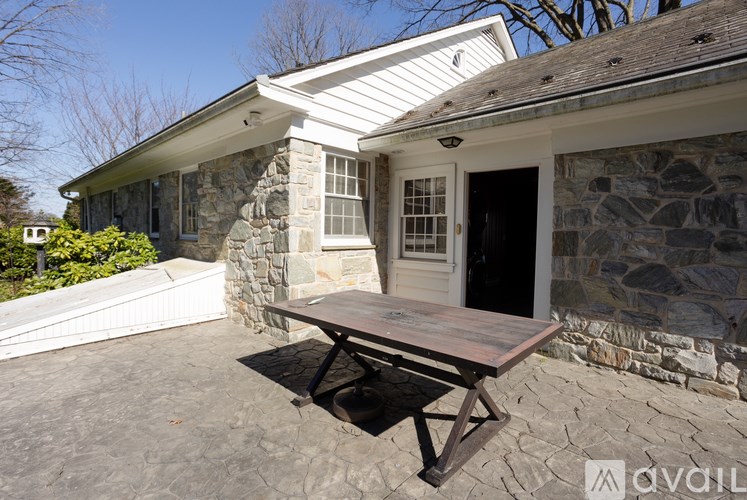 A stone house with a white roof and a wooden table outside.