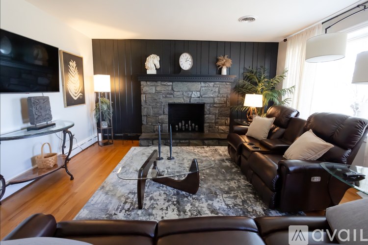A living room with a fireplace and a brown leather couch.