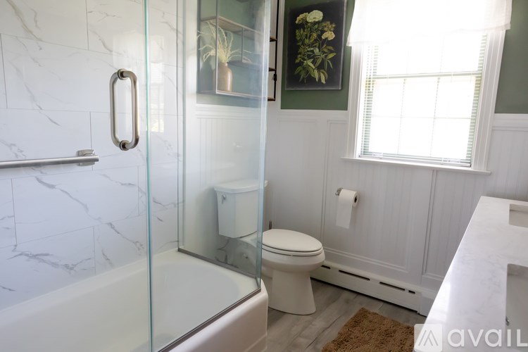 A white bathroom with a glass shower door and a toilet.