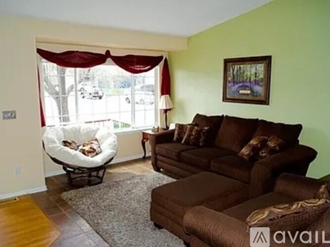 A living room with a brown couch and a white chair.