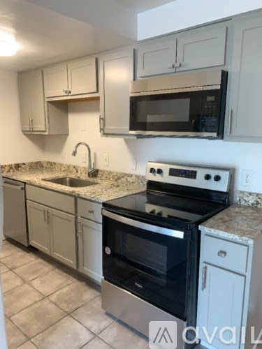 A kitchen with a stove, oven, microwave, and cabinets.
