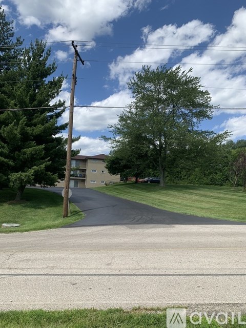 A street view with a house and trees in the background.