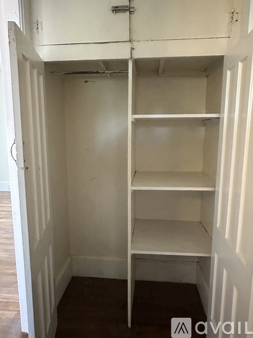 A small white closet with a shelf and a door.