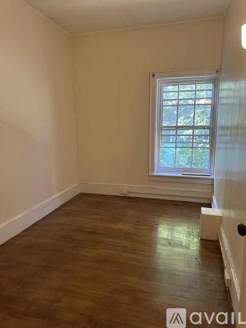 A room with a window and wooden flooring.
