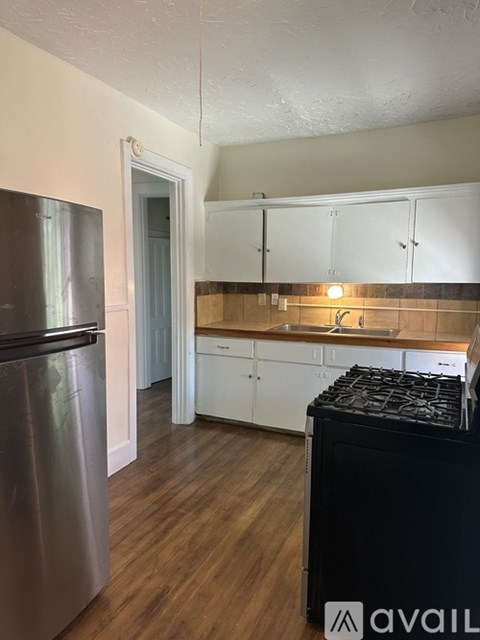 A kitchen with a black stove top oven and a stainless steel refrigerator.