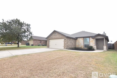 A house with a driveway and a tree in front of it.