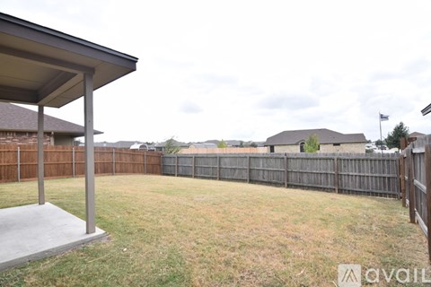 A backyard with a wooden fence and a covered patio area.