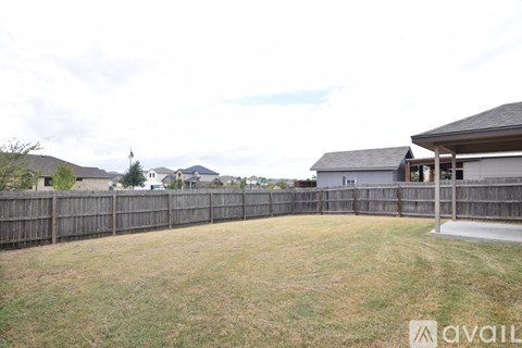 A backyard with a wooden fence and a house in the background.