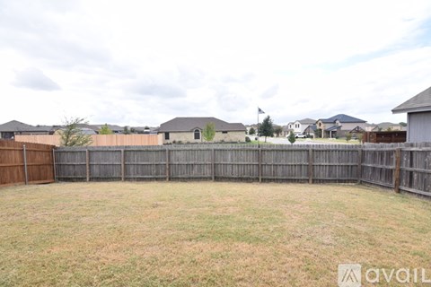 A backyard with a wooden fence and grassy field.