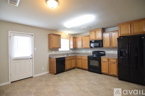 A kitchen with black appliances and wooden cabinets.