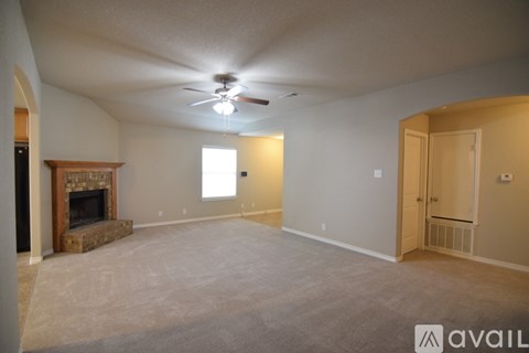 A spacious living room with a fireplace and a ceiling fan.