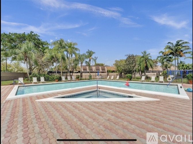 A pool surrounded by a brick patio and palm trees.