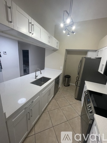 A kitchen with white cabinets and a black fridge.