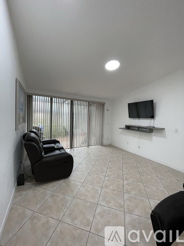 A living room with a black chair and a flat screen TV mounted on the wall.