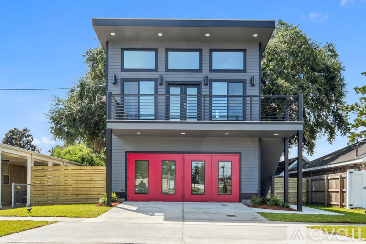 A modern house with a red door and a balcony.