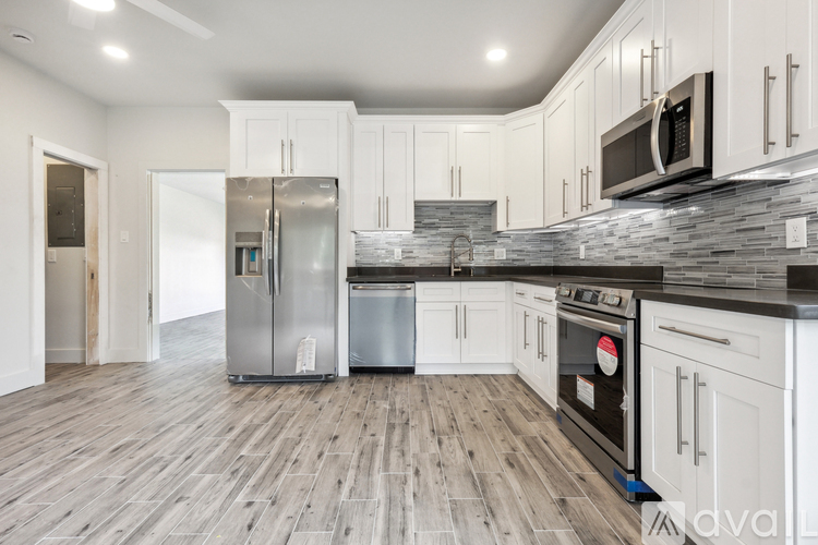 A kitchen with white cabinets and a wooden floor.