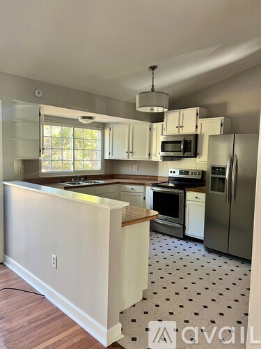 A kitchen with a white counter and black and white floor.