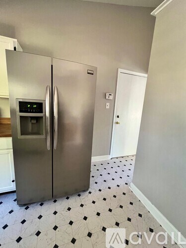 A stainless steel refrigerator with a digital display on the door stands in a kitchen.