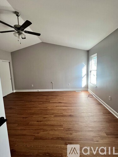 A room with a ceiling fan and wooden flooring.