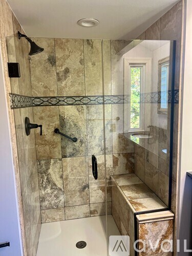 A shower with a glass door and a bench inside.