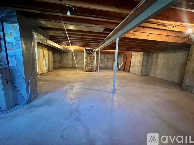 A spacious unfinished basement with concrete floors and exposed ceiling beams.