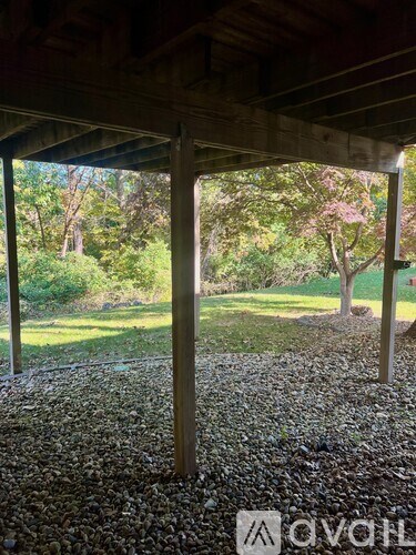 A gravel area under a wooden structure with a tree in the background.