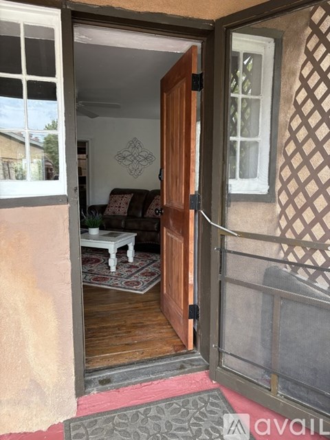 A wooden door opens to a living room with a couch and a table.