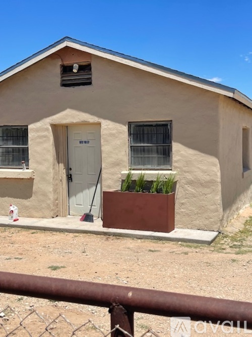 A small house with a white door and a window with bars.