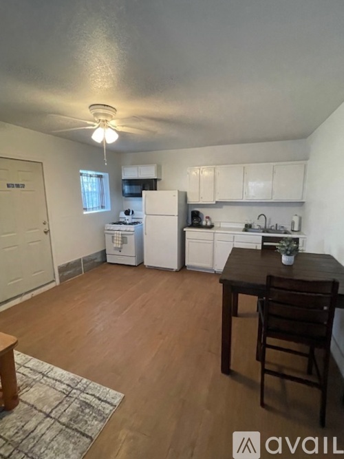 A kitchen with white appliances and wooden floors.