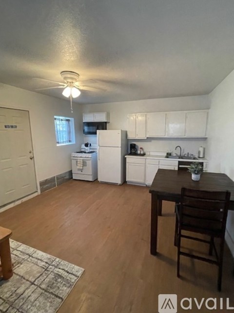 A kitchen with white appliances and wooden floors.