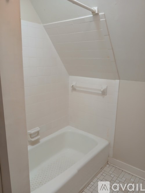 A white bathroom with a tub and a towel bar.