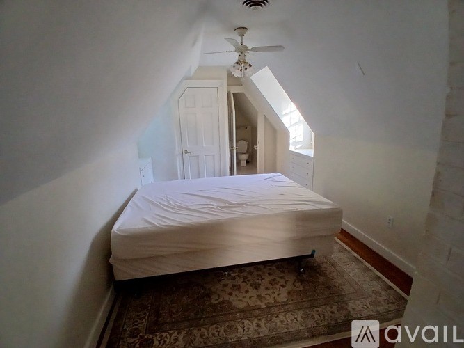 A bedroom with a bed, rug, and a ceiling fan.