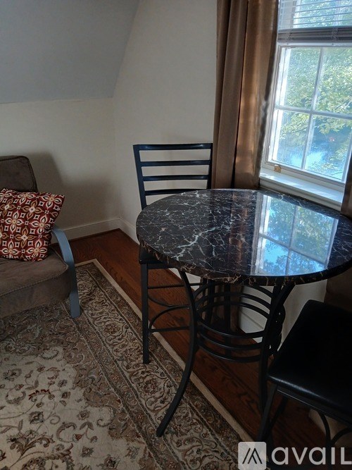 A black chair sits in front of a marble table.