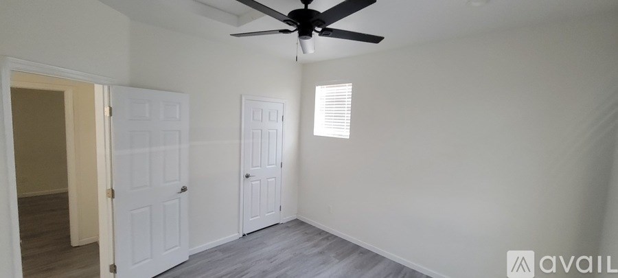 A room with a ceiling fan and two doors.