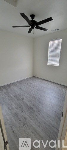 A room with a ceiling fan and a window with blinds.