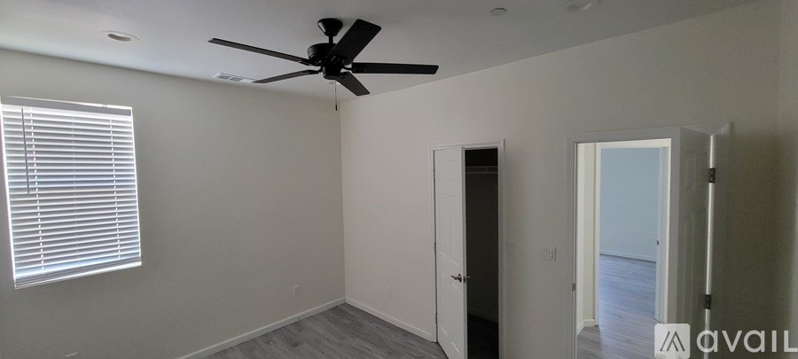 A room with a ceiling fan and a window with blinds.