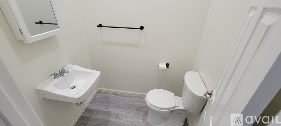 A white toilet in a small bathroom with a sink and a mirror.