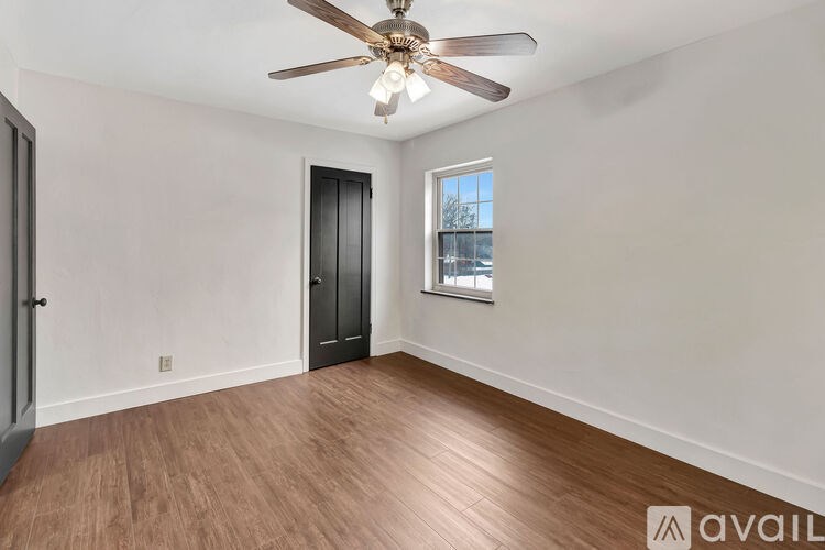 A room with a ceiling fan and wooden flooring.