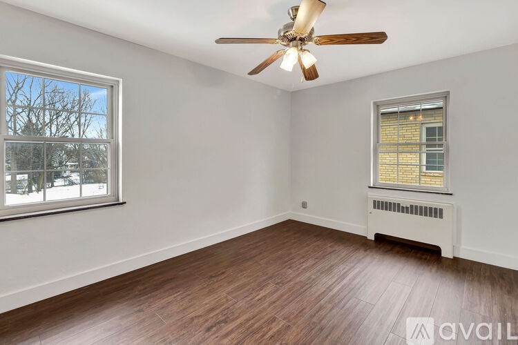 A room with a ceiling fan and two windows.