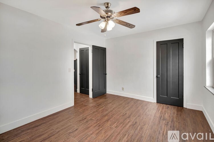 A room with a ceiling fan and two doors.