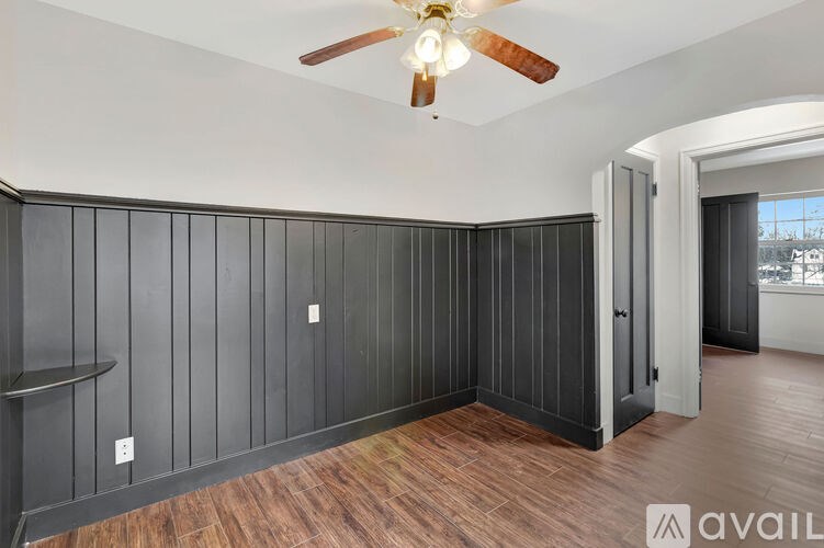 A room with a ceiling fan and wooden flooring.