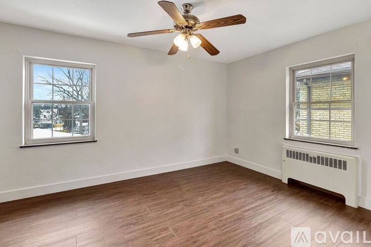 A room with a ceiling fan and two windows.
