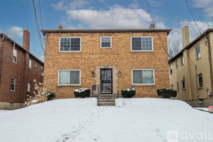 A brick house with a black door and windows is surrounded by snow.