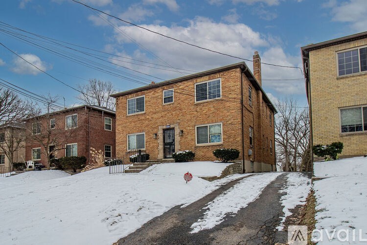 A brick house with a snow-covered ground in front.