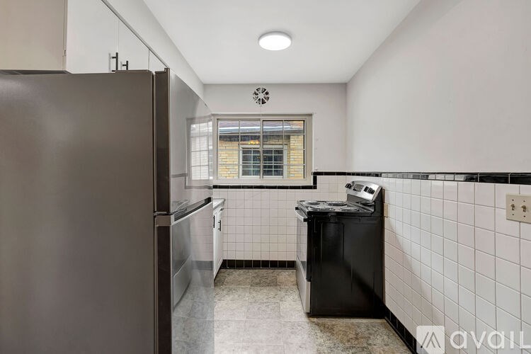 A kitchen with a black fridge and a black trash bin.