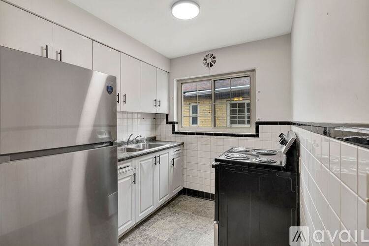 A kitchen with a stainless steel refrigerator, black dishwasher, and white cabinets.