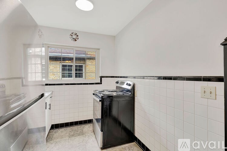 A kitchen with a black dishwasher and white tiled walls.