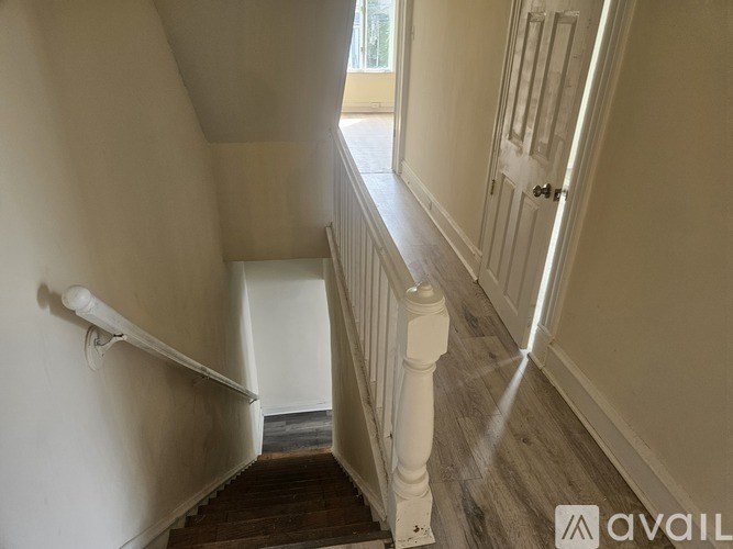 A staircase with a white railing and wooden steps leading to a door.