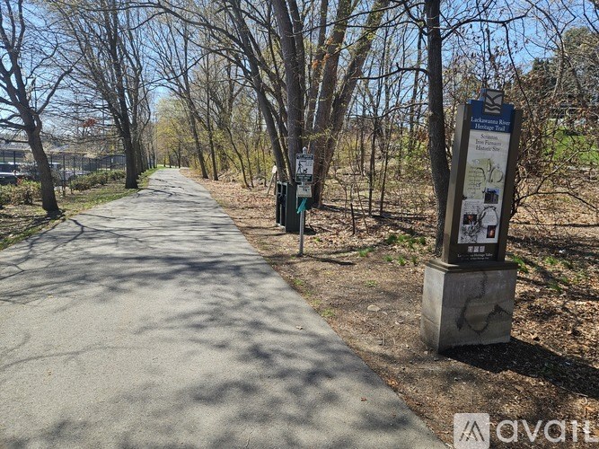 A paved path in a park with a sign on the right side.
