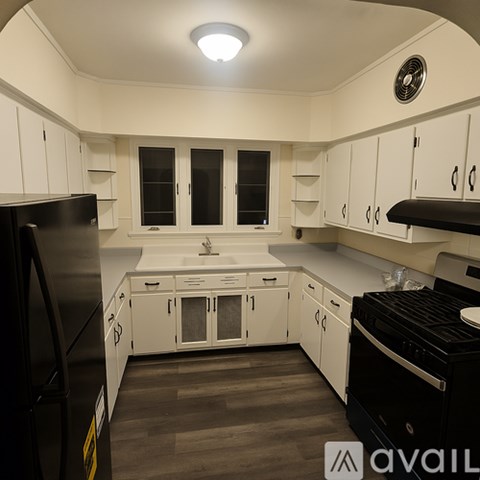 A modern kitchen with black appliances and white cabinets.